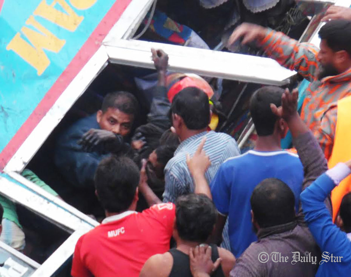 Local people rescue passengers from a bus that plunges into a ditch on Barisal-Jessore highway in Rajapur upazila of Jhalakathi, killing 10 people on Tuesday, December 23, 2014. Photo: Star