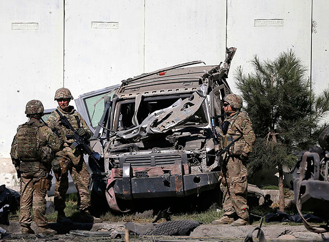 US troops keep watch near a damaged vehicle at the site of a suicide attack in Kabul September 16, 2014. A huge explosion rattled windows in Afghanistan's capital early on Tuesday, sending a plume of white smoke rising above eastern Kabul. Photo: Reuters