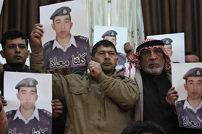 Relatives of Islamic State captive Jordanian pilot Muath al-Kasaesbeh hold his poster as they take part in a rally in his support at the family's headquarters in the city of Karak, January 31, 2015. The words on the portrait reads, 