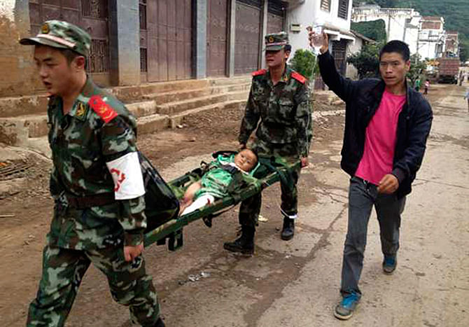 Paramilitary policemen carry an injured child on a stretcher as they carry out rescue operations after an earthquake hit Longtoushan township of Ludian county, Yunnan province August 3, 2014. Photo: Reuters