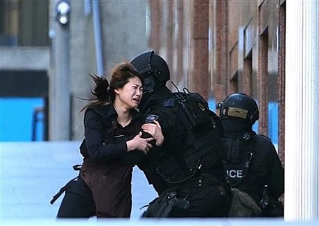 A hostage runs to armed tactical response police officers for safety after she escaped from a cafe under siege at Martin Place in the central business district of Sydney, Australia, Monday, Dec. 15, 2014. Photo: AP