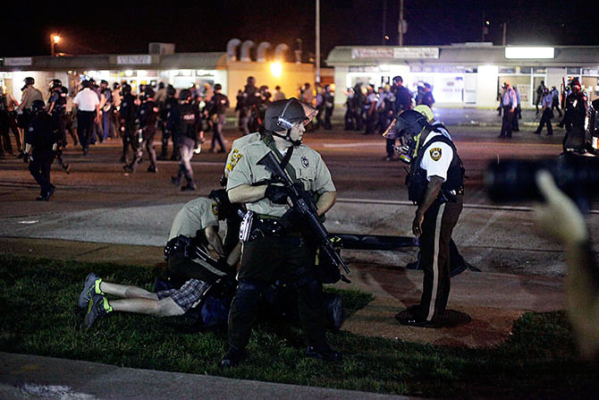 Police detain a demonstrator during a protest against the shooting death of Michael Brown in Ferguson Missouri August 18, 2014. Police fired tear gas and stun grenades at protesters on Monday after days of unrest sparked by the fatal shooting of unarmed black teenager Michael Brown by a white policeman.Photo: Reuters