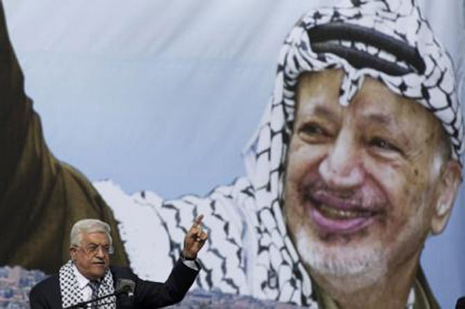 Palestinian President Mahmoud Abbas gestures beneath a poster of the late Palestinian leader Yasser Arafat, during a rally marking the tenth anniversary of Arafat's death, in the West Bank city of Ramallah November 11, 2014. Photo-Reuters