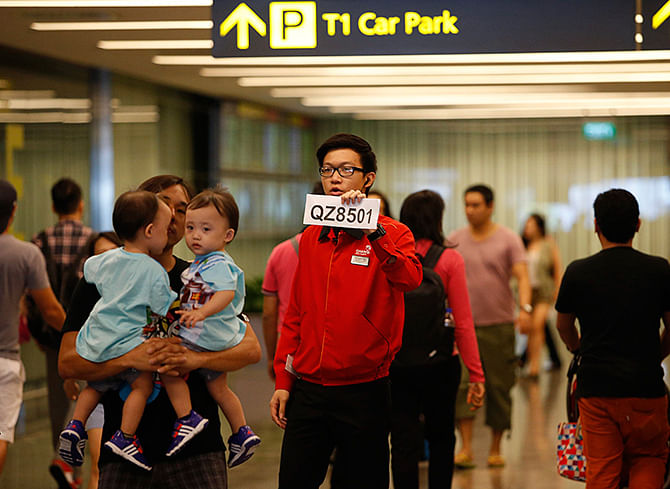 A Changi Airport staff holds up a sign to direct possible next-of-kins of passengers of AirAsia flight QZ 8501 from Indonesian city of Surabaya to Singapore, at Changi Airport in Singapore December 28, 2014. Photo: Reuters