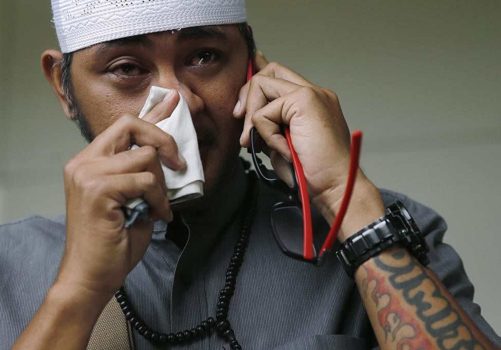 An Indonesian man, whose wife is a passenger onboard the missing AirAsia flight QZ8501, makes a phone call at a waiting area in Juanda International Airport, Indonesia. Photo: Reuters