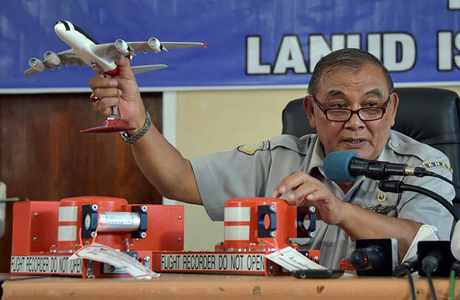Tatang Kurniadi, the head of the National Transportation Safety Committee (KNKT), speaks to journalists while using samples of the flight data recorder (FDR) (pictured at R on table) and cockpit voice recorder (CVR) (L on table) during a press conference in Pangkalan Bun on January 13, 2015. Photo: AFP/Adek Berry