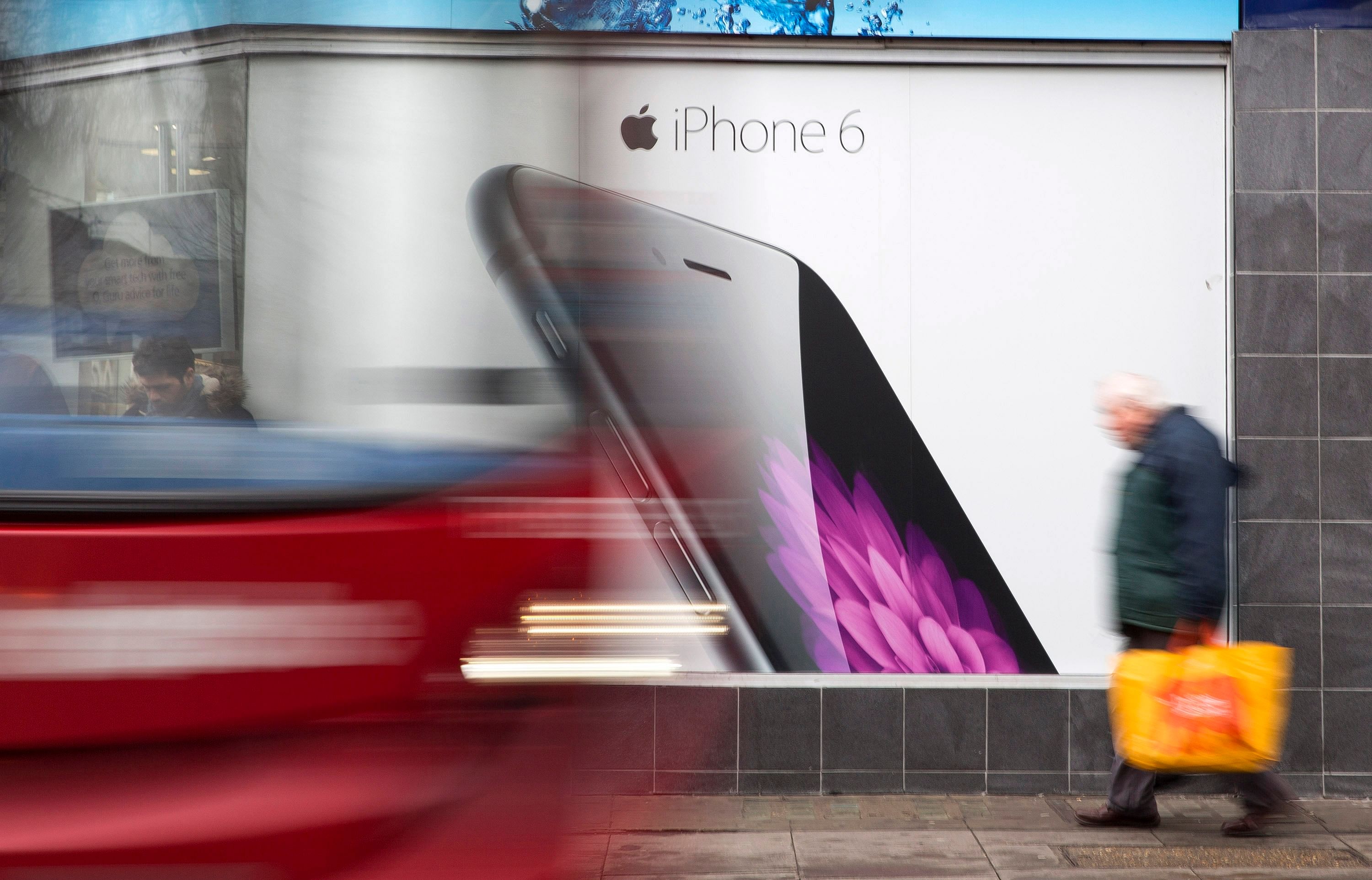 A bus and pedestrian pass an advertisement for the Apple iPhone 6 in north London January 28, 2015. Photo: Reuters