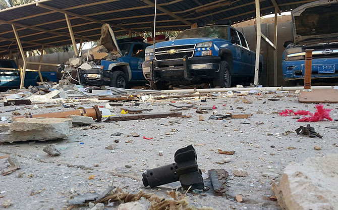 Police vehicles are parked next to debris in the Anbar province town of Hit, October 6, 2014. Iraqi forces backed by Shi'ite volunteer fighters are fighting to retake control of the western Iraqi town of Hit from the insurgents of the Islamic State, residents said. Photo: Reuters