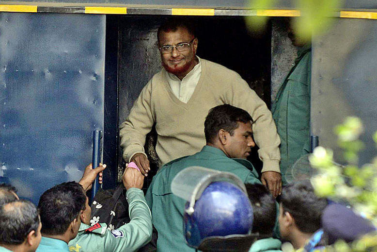 War criminal ATM Azharul Islam, the assistant secretary general of Jamaat-e-Islami, waves at reporters as law enforcers take him to a prison van after International Crimes Tribunal-1 awarded him death penalty on December 30 for his crimes against humanity during the Liberation War in 1971. Photo: Anisur Rahman 