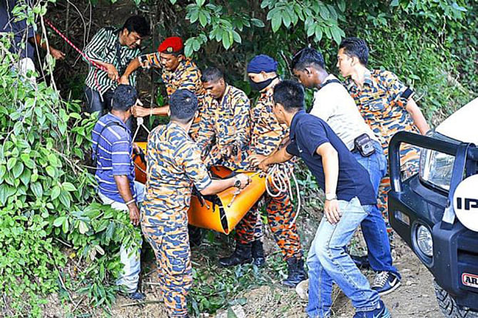 Policemen and firemen carrying Hussin's body down the slope after he was killed in what is believed to be a botched kidnap attempt at Bukit Relau in Jalan Bukit Gambier.Photo taken from Malaysian daily The Star