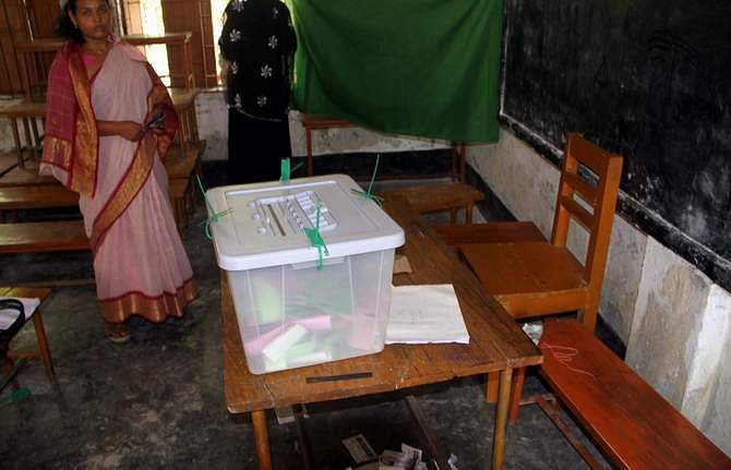 A woman is seen waiting beside a ballot box to cast her vote at Rajgur Government Primary School polling centre in Babuganj upazila of Barisal Saturday.  Seven chairman candidates in four districts boycott the third phase upazila elections alleging ouster of their agents and voters by ruling Awami League men. Photo: STAR  