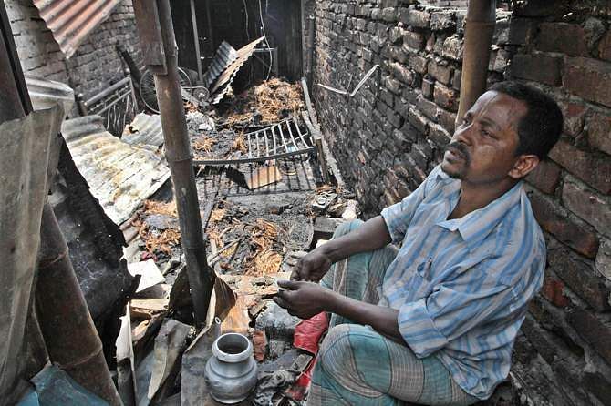 A man sits inside his burnt house at a Bihari camp in Mirpur area of the capital on Saturday. Photo: STAR