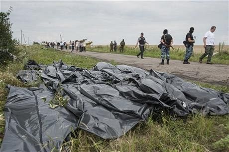 Pro-Russian fighters walk on a road with victims' bodies lying in bags by the side at the crash site of a Malaysia Airlines jet near the village of Hrabove, eastern Ukraine, Saturday. Photo: AP