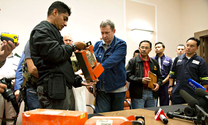 A Malaysian investigator, left, takes a black box from MH17 as it is handed over by a Donetsk People's Republic official on July 22. Photo: AP