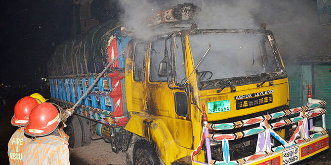 Fire fighters try to extinguish the flames in a rice-laden truck after unidentified miscreants torched it at Station Road in Bogra town on Wednesday. Photo: Star
