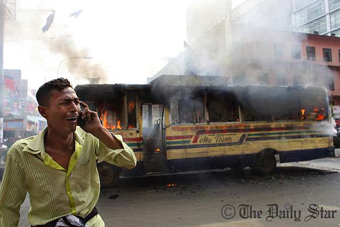 Horrified driver stand in front of his bus as miscreants set fire to it in front of Baitul Mukarram National Mosque on January 4. Photo: STAR