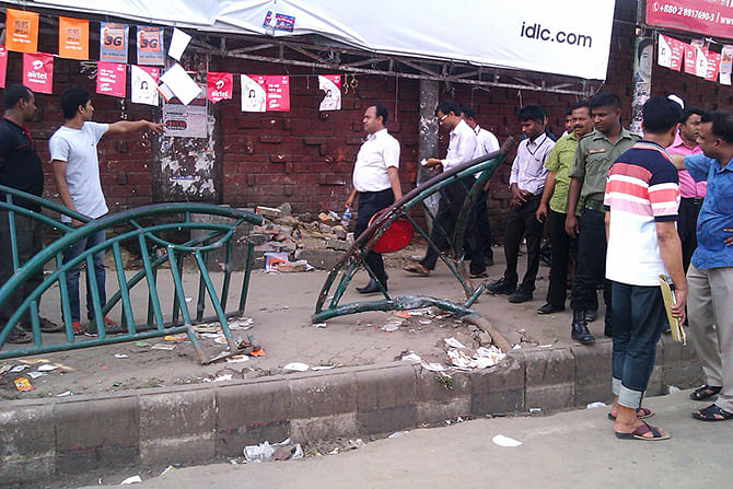 Passers-by gather near smashed footpath railings on airport road in the capital on Wednesday. Four pedestrians including a woman were crushed under a bus after the driver had lost control over the wheels in that very spot. Photo: Shaheen Mollah 