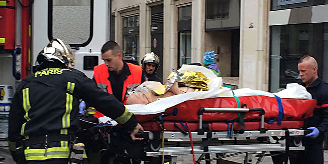 Policemen and rescuers take a victim of the shooting to hospital after the incident near the office of Charlie Hebdo. Photo: AFP