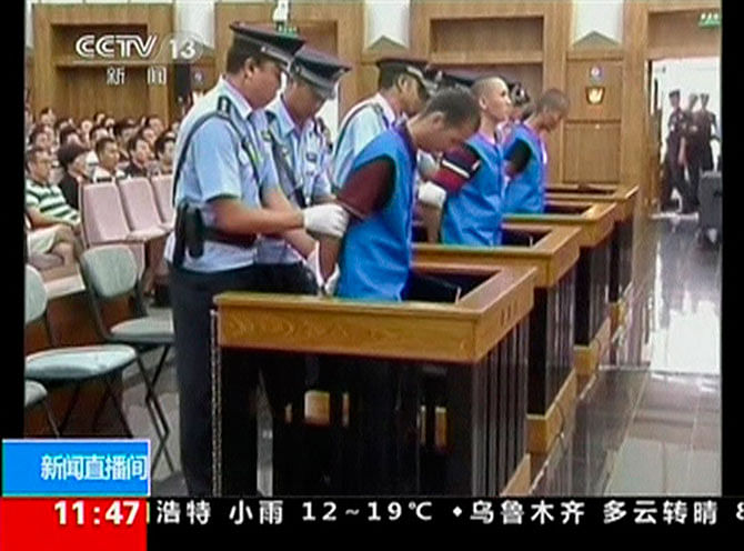 Defendants are escorted by police officers at a courtroom in Kunming City during the trial of four people accused of participating in an attack at a train station in southwestern China, in this still image taken from video September 12, 2014. Photo taken from Reuters