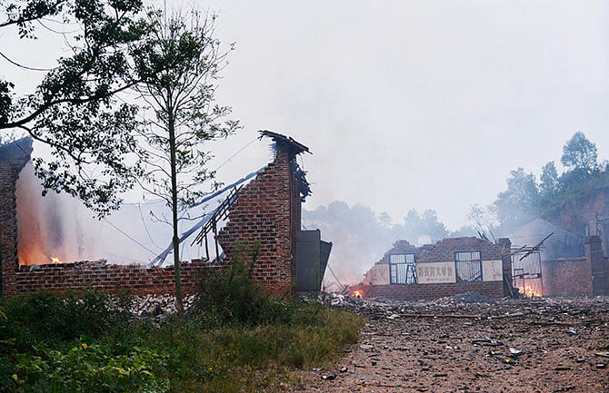 Ruins of a fireworks plant is seen on fire after an explosion in Liling, Hunan province September 22, 2014. Twelve people were confirmed dead and 33 others injured in the accident on Monday, local authorities said. Photo: Reuters