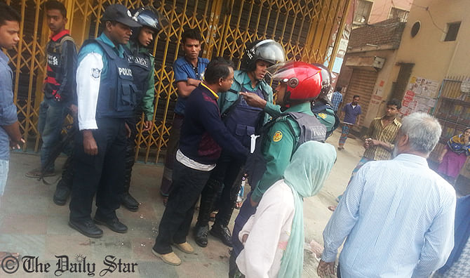 Policemen talk to passersby in front of a closed shop on Kazi Nazrul Islam Avenue at Farmgate in Dhaka after pro-hartal activists blasted several crude bombs there Sunday morning. Photo: SAM Jahan