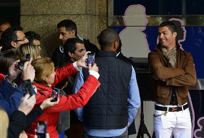 This AFP photo taken in December, 2013 shows football fans taking picture of Real Madrid's Portuguese forward Cristiano Ronaldo (R) during the unveiling of his wax figure at the Wax Museum of Madrid.