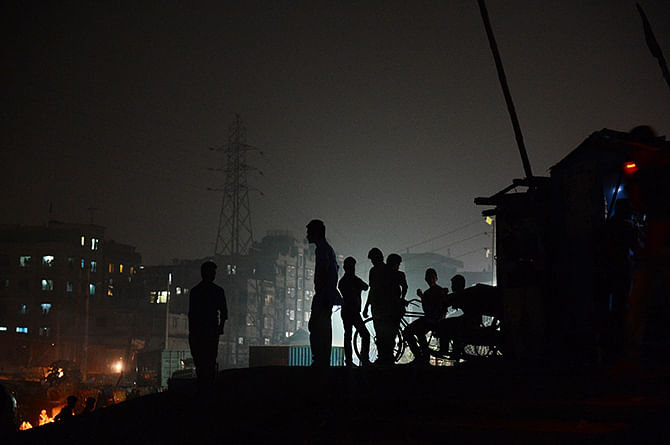 Residents of a depressed neighborhood in the old part of Dhaka stand outside small shops on the banks of the Buriganga river on January 3, 2014. Photo: Getty Images