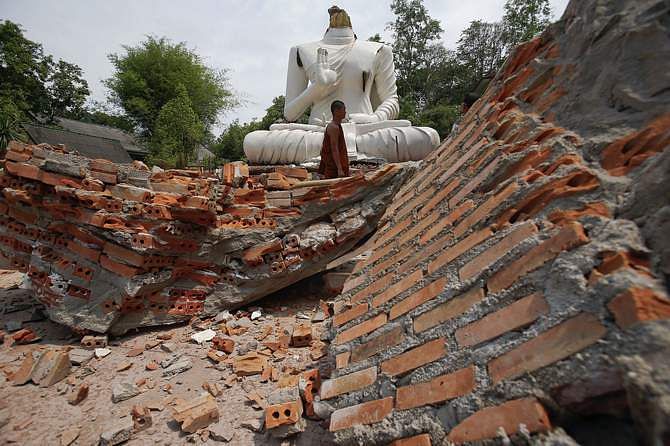 A Buddhist monk walks in front of a Buddha statue damaged in the earthquake at the Udomwaree temple in Chiang Rai, in northern Thailand May 6, 2014. Photo: Reuters