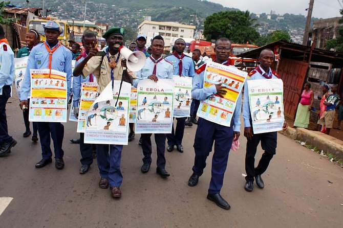 Members of a Unicef-supported social mobilisation team walk on a street, carrying posters with information on the symptoms of Ebola and best practices to help prevent its spread, in Freetown, Sierra Leone, in this handout photo courtesy of Unicef taken in August 2014. This photo is taken from Reuters.
