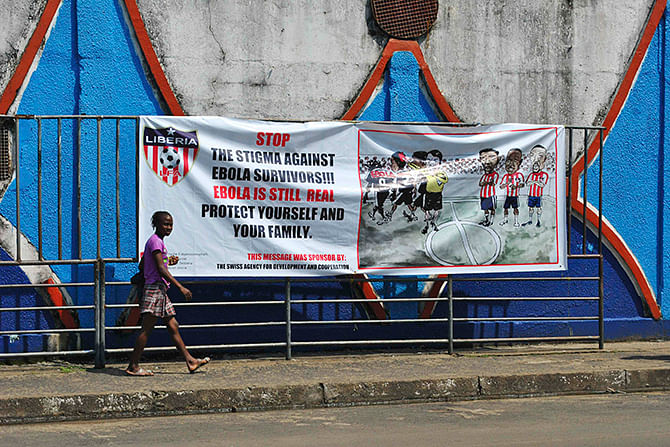A woman walks pass an Ebola virus awareness campaign poster in Monrovia, December 8, 2014. Photo: Reuters