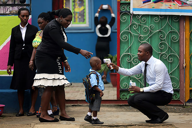 A school official takes a pupil's temperature using an infrared digital laser thermometer in front of the school premises, at the resumption of private schools, in Lagos September 22, 2014. Photo: Reuters