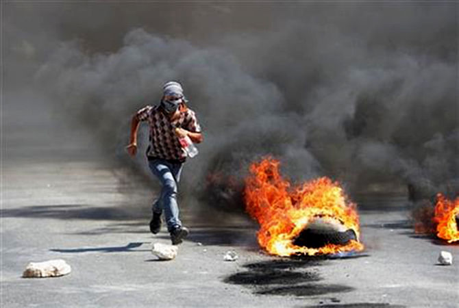 A Palestinian protester runs away from Israeli soldiers during clashes, following a protest against the Israeli military action in Gaza, in the West Bank city of Nablus on Friday, Aug 22, 2014. Photo: AP