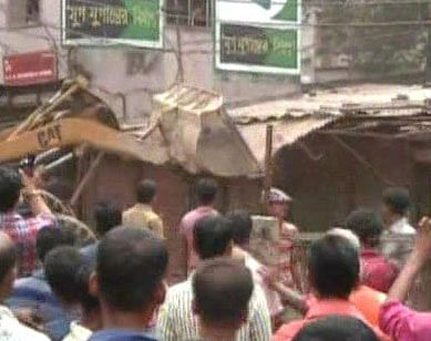A bulldozer is seen demolishing illegal structures set up along rail tracks at Moghbazar in Dhaka Sunday. Photo: TV grab
