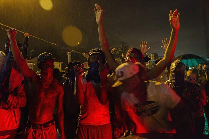 Protesters gesture as they stand in a street in defiance of a midnight curfew meant to stem ongoing demonstrations in reaction to the shooting of Michael Brown in Ferguson, Missouri August 17, 2014. Photo: Reuters