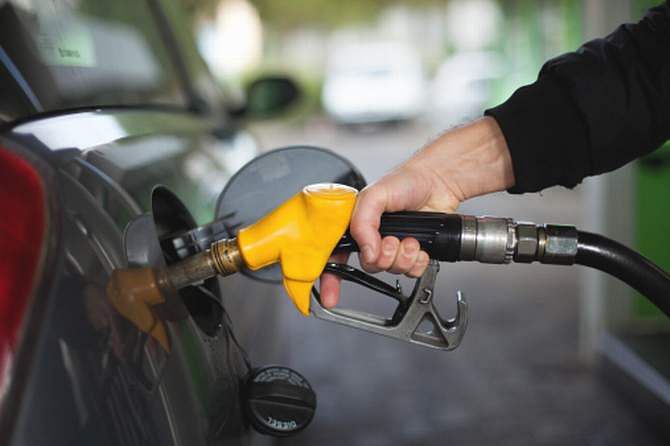 Hand of man fueling up a vehicle with a yellow gas pump. Photo: Getty Images