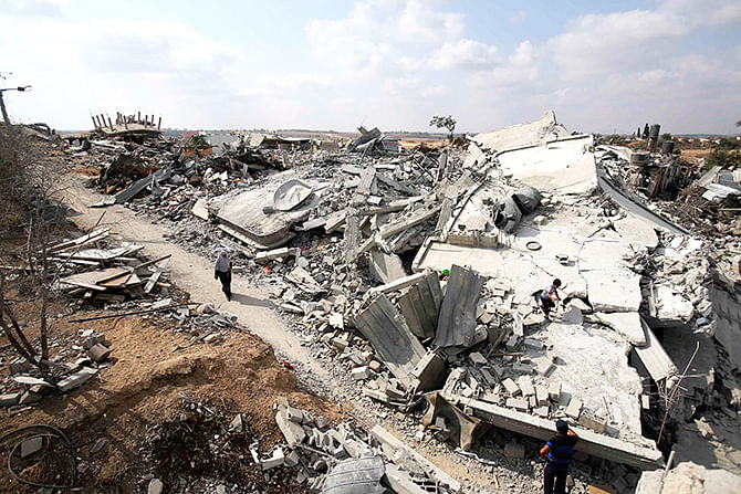 A Palestinian woman walks past the ruins of houses which witnesses said were destroyed during the Israeli offensive in Johr El-Deek village near the central Gaza Strip August 17, 2014. Photo: Reuters