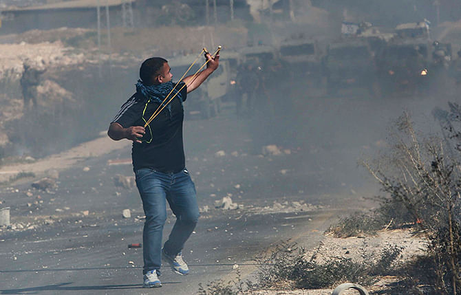 A Palestinian protester uses a slingshot to hurl stones toward Israeli troops during clashes following a demonstration against the Israeli offensive in Gaza, at the Beit Fourik checkpoint near the West Bank of Nablus August 8, 2014. Photo: Reuters