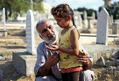 A relative guides a girl in prayer at the grave of their loved one in a cemetery in Gaza city, northern Gaza Strip, Monday. Photo: AP