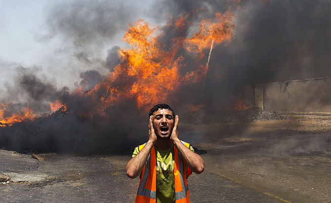 Palestinian firefighters try to extinguish fire at UN storehouse after an Israeli military strike in an area west of Gaza City on July 12, 2014. Photo: Getty Images