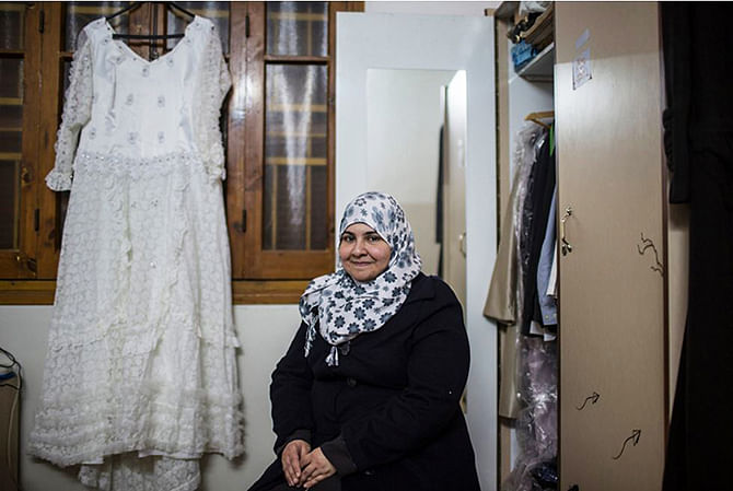 Dalia Shurrab, with her wedding gown, at her home in Khan Younis in southern Gaza. Her fiancé, Rashed Sameer Faddah, lives in the West Bank city of Nablus. Their inability to travel freely between the territories has delayed their marriage plans. Photo: New York Times