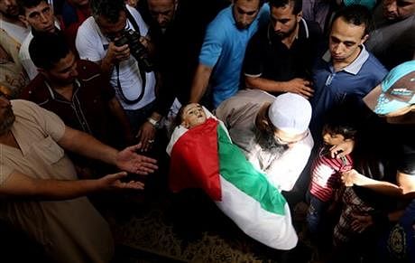 Palestinian mourners gather around the lifeless body of one year-old Rizk Hayek, who was killed Friday by an Israeli tank shell, during his funeral in Gaza City, Saturday. Photo: AP