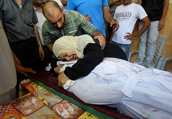 The mother-in-law of Palestinian translator Ali Shehda Abu Afash, whom medics said was killed when unexploded munitions blew up, mourns over his body during his funeral in Gaza City August 13, 2014. Photo: Reuters