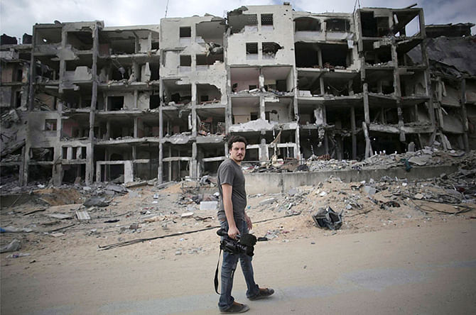 Associated Press video journalist Simone Camilli walks against a backdrop of destroyed buildings in Beit Lahiya in the Gaza Strip August 11, 2014. Italian journalist Camilli, three Palestinian bomb disposal experts and two other people were killed in Gaza on Wednesday when unexploded munitions blew up, medical officials and police said. Photo: Reuters