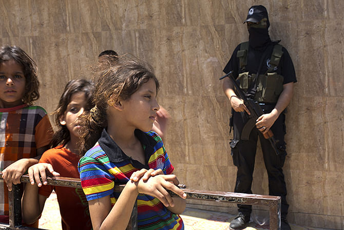 A Palestinian militant stands guard as a young girl looks on during the funeral of two Palestinian militants who were killed during an Israeli air strike the night before, on July 7, 2014 in al-Bureij refugee camp in the central Gaza Strip. Israeli air strikes killed at least seven militants in Gaza overnight as clashes over the kidnap and murder of a Palestinian teenager raged into the early hours of July 7. Photo: AFP/ Getty Images