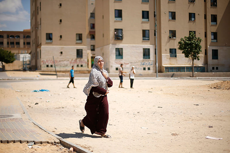 A Palestinian woman flees her house following what witnesses said was a nearby air strike on an apartment in Beit Lahiya in the northern Gaza Strip August 10, 2014. Photo: Reuters
