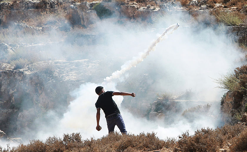 A Palestinian protester throws back a tear gas canister fired by Israeli soldiers during clashes following a demonstration against Israeli military action in Gaza, at the Beit Fourik checkpoint near the West Bank city of Nablus August 15, 2014. Photo: Reuters