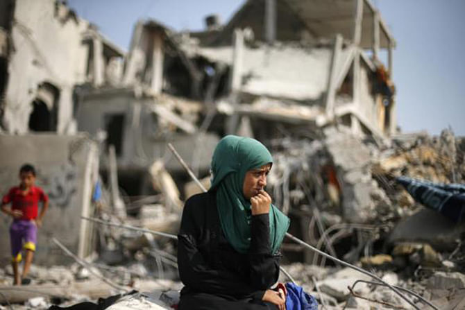 A Palestinian woman sits on the remains of her destroyed house after returning to Beit Hanoun town, which witnesses said was heavily hit by Israeli shelling and air strikes during the Israeli offensive, in the northern Gaza Strip August 5, 2014. Photo: Reuters 