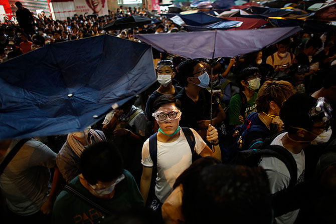 Pro-democracy protesters hold umbrellas as they face policemen in the Mongkok shopping district of Hong Kong October 18, 2014. About a thousand Hong Kong pro-democracy activists recaptured parts of a core protest zone early on Saturday, defying riot police who had tried to disperse them with pepper spray and baton charges. Photo: Reuters
