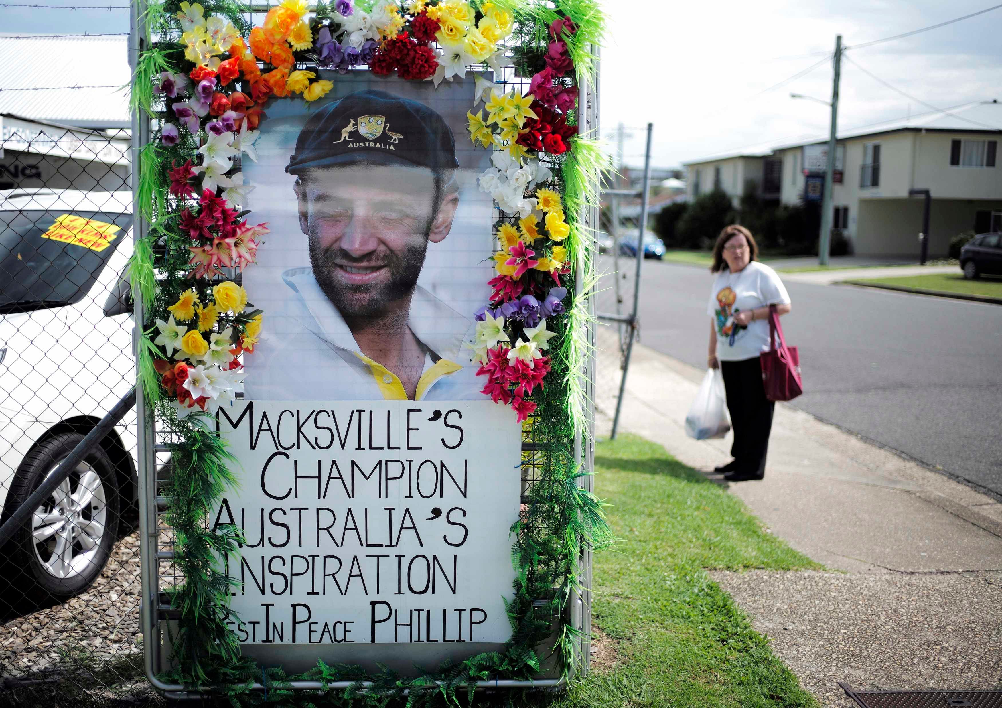 A local resident is pictured alongside a tribute to deceased Australian cricketer Phillip Hughes as his hometown prepares for his funeral in Macksville December 2, 2014. Photo: Reuters