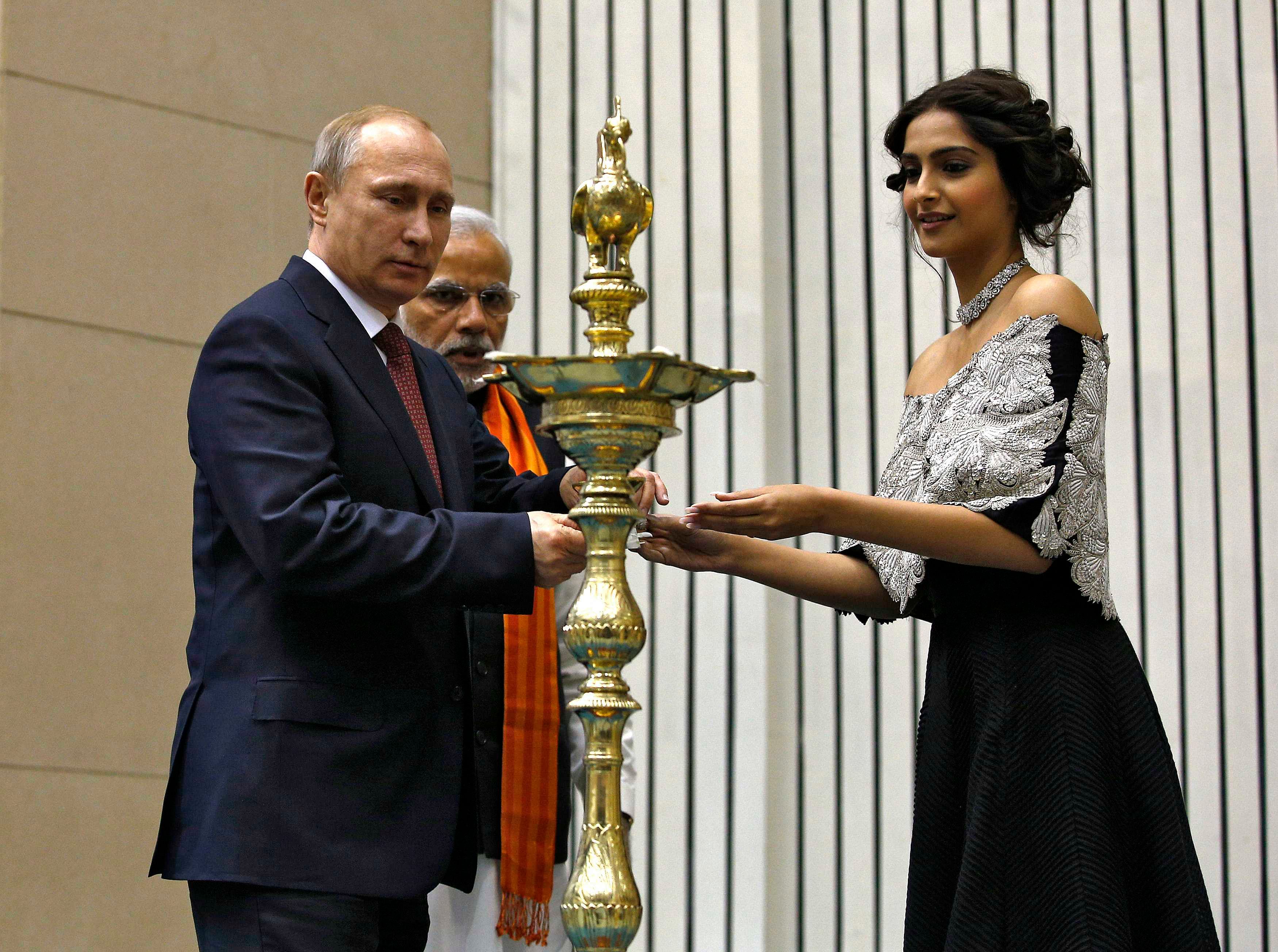 Bollywood actress Sonam Kapoor (R) helps Russian President Vladimir Putin (L) to light a traditional Indian oil lamp as India's Prime Minister Narendra Modiwatches during the inauguration of World Diamond Conference in New Delhi December 11, 2014. Photo: Reuters